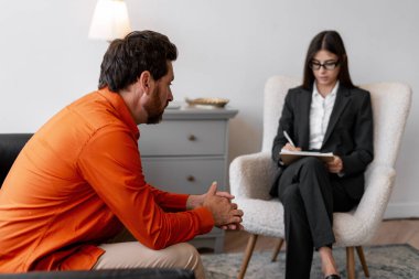 Üzgün, üzgün bir adam kadın psikologla terapi yapıyor, not alıyor. Kadın doktor hastayla konuşuyor. İletişim konsepti