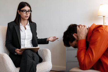 Stresli bir hastayla konuşan, açıklama yapan, ona yardım eden, modern ofiste rahat bir koltukta oturan bir psikolog. Psikoloji terapi konsepti