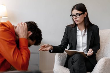 Psikolog, adamın akıl sağlığı desteğine ihtiyacı olduğunu söyledi. Üzgün erkek hasta depresyonda, modern ofiste birlikte oturuyor. Ruh sağlığı konsepti