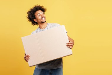 Afro saç stili mutlu bir genç elinde karton bir kutu, metin için fotokopi alanı ile yan bakıyor
