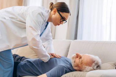 Doktor evde yaşlı bir hastaya acil kalp masajı yapıyor. Kanepede baygın yatan yaşlı bir adam. Profesyonel yoğunlaşmacı olgun hastalara yardım ediyor. İlk yardım kavramı