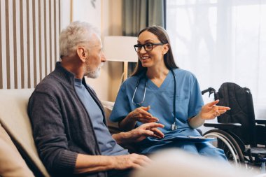 Gülümseyen mutlu kadın, modern klinikte oturan yaşlı bir adama danışmanlık yapan hemşire. Hastanede güzel bir doktor ve hasta birlikte. Sağlık hizmeti kavramı