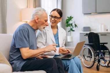 Doktor, kıdemli bir adama ev sağlık sigortası konusunda yardımcı oluyor. Üst düzey bir adam da dizüstü bilgisayar kullanıyor. Oturma odasında postaları kontrol eden olgun bir hasta. Çevrimiçi teknoloji kavramı