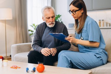 Bakıcı kadın, üst düzey bir adama sağlık konusunda danışıyor, not tutuyor, not alıyor. Kadın doktor evde erkek hastayla birlikte oturuyor. Danışmanlık konsepti