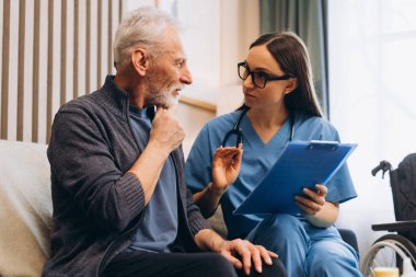 Üst düzey bir adam modern oturma odasında oturan hemşireden ev sağlığı danışmanlığı alıyor. Güzel bir kadın olgun bir hastaya danışıyor. Destek konsepti