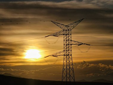 Silhouette of high voltage tower at sunset with clouds. clipart