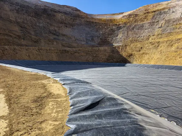 Bir açık maden ocağının dibinde jeosentetik malzemelerle su havuzları inşa etme süreci.