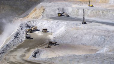 Ağır madencilik makineleri açık bir maden ocağında mineraller çıkarıyor.