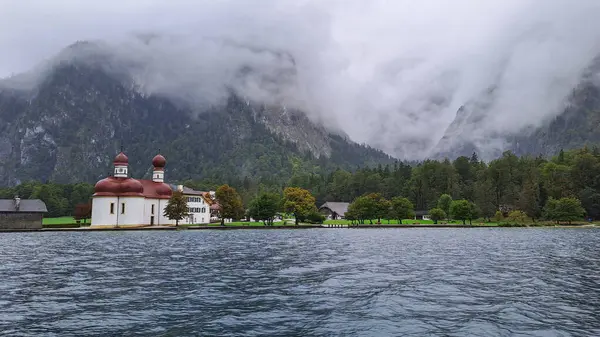 Göle bakan bir ev, orman dağlarının yanında ve sisli bir sürü bulut.