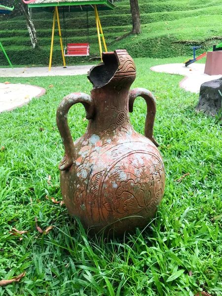 stock image broken jug with green grass background