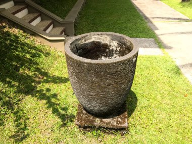 Betondan yapılmış çöp kutusu ve yeşil çimen arka planı ve yapraklardan gölgeler.