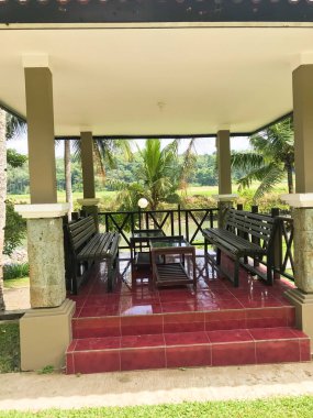 İki yan sandalye ve ortasında ahşaptan yapılmış kırmızı seramikli bir masa.