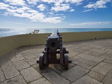 Demir Top, mavi gökyüzüyle Engin Okyanus Ufkunu işaret ediyor. Demir tekerlekler üzerinde tarihi ve eski toplar.