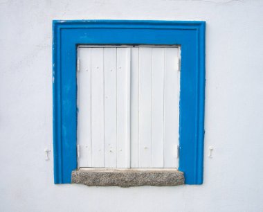 Portimo 'da tipik bir evde geleneksel Algarve penceresi. Ahşap pencere mavi süslemeli ve beyaz duvarlı..