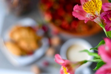 Pembe arkaplan, çiçekler, meyveler ve kahveyle kahvaltı.