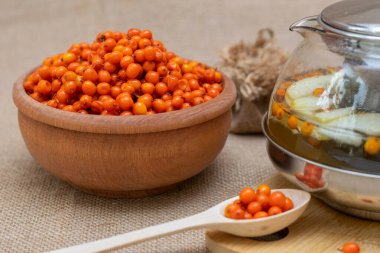 Sea buckthorn in a wooden bowl, wooden spoon and sea buckthorn tea