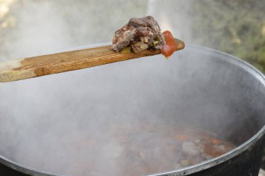 Kazanda, sıcak buharın üstündeki tahta kaşıkta et hazır.
