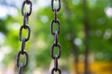 Doğal yeşil zemin üzerinde dikey metal zincir, sınırlar ve özgürlük kavramı