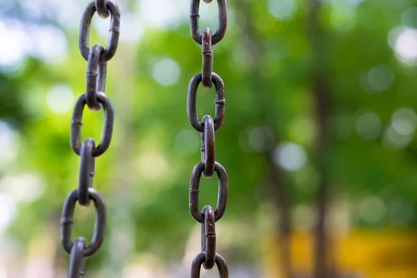 Doğal yeşil zemin üzerinde dikey metal zincir, sınırlar ve özgürlük kavramı