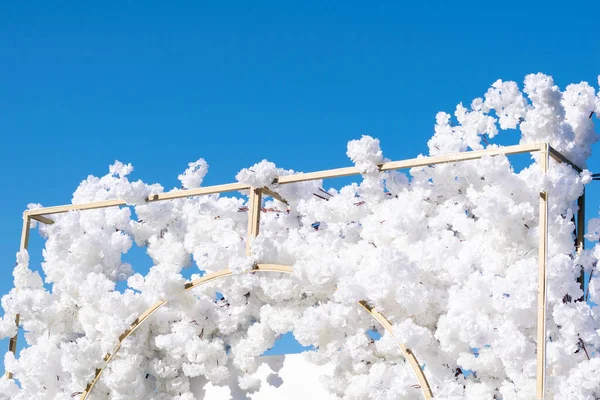 Düğün için metal paneldeki beyaz dekoratif çiçekler, mavi gökyüzü.