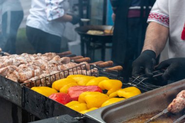 Aşçının eli eti ızgarada döndürür. Izgara sebze. Sokak yemeği..