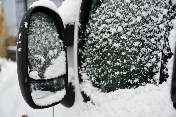 Araba aynası ve pencere karla kaplı.