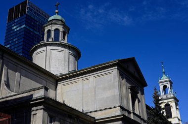 Modern bir gökdelenin arka planına karşı tarihi bir kilise.