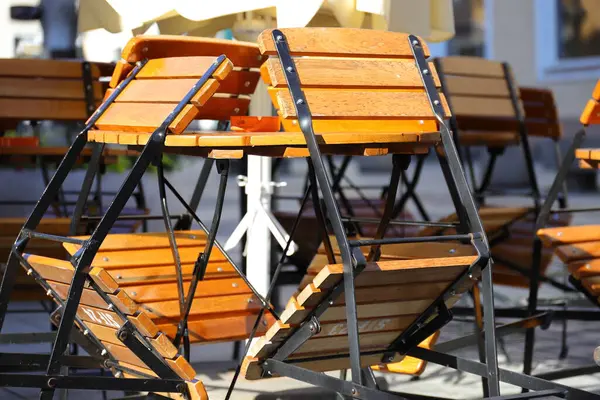 Tahta masaya yaslanmış renkli sandalyeler.