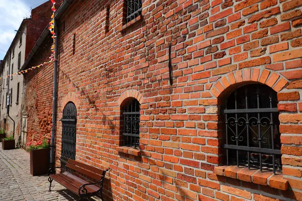 Pencerelerinde parmaklık olan kırmızı tuğlalı bir ev.