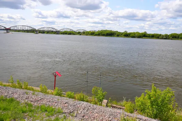 Nehrin üzerinde kırmızı bir çatı ve arka planda bir köprü.