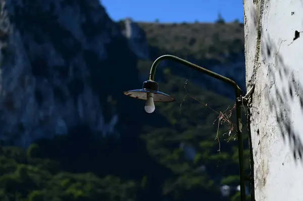 A rusty street lamp on the wall of a building