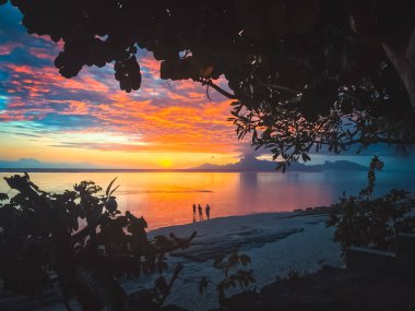 Doğa tropikal deniz, parlak günbatımı manzarası okyanus suyuna yansıyan renkli gökyüzü. İnsanlar turist siluetini plajda dinlendirirler..