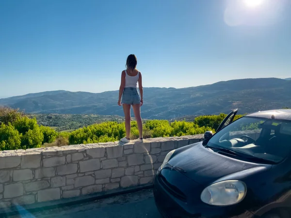 Woman watching beautiful nature landscape of Cyprus island vinnary valley. Back view of girl treveler enjoying nature. Car travel, active lifestyle, holidays, tourism. Amazing natural summer scenery.