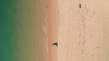 Kişi deniz kıyısında kumsal havası manzarası boyunca yürür. Yaz tatili geçmişi. Tropikal adanın tepesinde, kristal su dalgaları. İdeal egzotik sahilde beyaz şapkalı bir kadın. Seyahat tatili