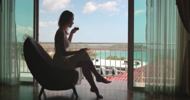 Genç zarif bayan balkonda kahve içiyor ve okyanus manzarasının tadını çıkarıyor. Phuket, Tayland 'da kadın rahatlığı. Açık hava yaşam tarzı yaz tatili tatili için tropik adaya seyahat. Mükemmel sabah.