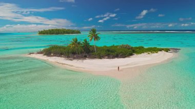 Turkuvaz suları ve yemyeşil bitki örtüsüyle çevrili tropikal bir adada gezinen bir kadının büyüleyici hava görüntüsü barış ve özgürlüğü çağrıştırıyor. Lüks ve egzotik tatiller için ideal.