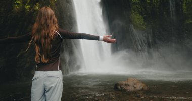 Turist kadın güçlü şelale Terjun Munduk, Endonezya, Bali adasında ayağa kalkar. Kadın pozu, arka plan, Güzel doğa manzarası. Seyahat, turizm, tatil