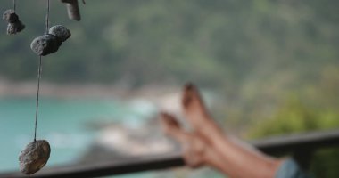 Kadın, ayakları tropik bir cennette rahatlatıcı bir anın tadını çıkarıyor. Tamamen sakin bir atmosfere dalmış, doğa ile çevrili ve mutlu hissediyor.