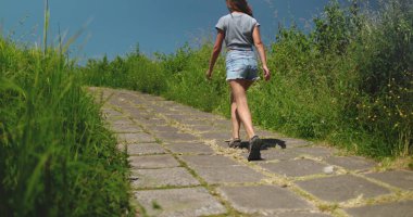 Ubud, Bali, Endonezya 'daki güzel Campuhan Tepesi Yürüyüşü' nde uzun otların yanında kırsal yolda yürüyen bir kadın. Doğadaki huzurlu yolculuğunu yakalar..