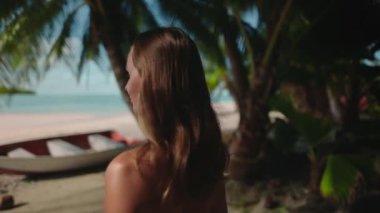 Kadın, kumlu sahilde, açık bir gökyüzünün altındaki yüksek palmiye ağaçlarının yanında dururken rahatlıyor. Kumsal istirahatı, seyahat, turizm. Tatil tatili için Cennet 'e tropikal adaya gidiyoruz. Arka plan yavaş çekim