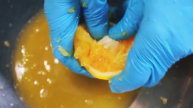 Şef portakal suyunu sıkıyor. Mavi eldivenli kadın demir kasede taze narenciye eziyor. Salata sosuna başla. Profesyonel restoranda yemek pişirmek, malzemeleri hazırlamak. Üst alt görünüm