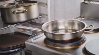 Lokantadaki şef tavada soğan ve yağ kızarttı. Kadın aşçı elleri mavi eldivenli, malzemeleri demir tavaya koyuyor. Lokanta mutfağında yemek pişirmek, sağlıklı beslenme düzeni.