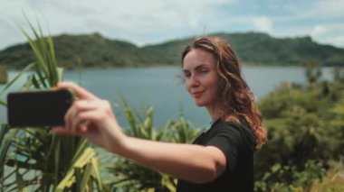 Kadın, tropikal ormanların ve dağ gölü manzarasının tadını çıkarırken selfie çekiyor. Doğa özgürlüğü macerası, mutlu tatiller video çağrısı, kız turist açık hava. Seyahat, turizm, Polinezya 'da tatil