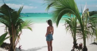 Filipinler 'deki Boracay Adası' nın beyaz kumlu sahilinde kendine güvenen bir kadın, bikini kıyafetiyle güneş ve denizin tadını çıkarıyor..