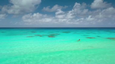 Kız sakin tropikal okyanuslardan, turkuaz sudan, parlak güneşli bulutlardan hoşlanıyor. Kadın sakin, kristal sığ deniz, doğal deniz manzarası. Yaz tatilindeki kadın turist.