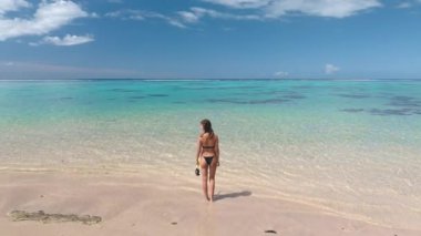 Kumsalda duran bikinili kız güzel egzotik doğa manzarasının tadını çıkarıyor. Şnorkel maskeli bir kadın aktif hayatın tadını çıkarıyor. Yaz tatilinde açık hava seyahati. Tahiti, Fransız Polinezyası
