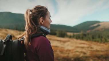 Turist kız sırt çantalı dağ sonbahar manzarasının tadını çıkarıyor. İnanılmaz doğal bir geçmişi var. Seyahat, yürüyüş, özgürlük ve aktif yaşam tarzı konsepti. Karpat Dağları, Ukrayna, Avrupa. Yavaş çekim geri görünümü