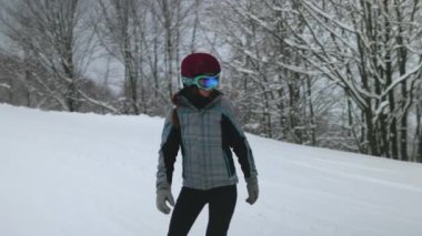 Bir snowboardcu bulutlu bir kış gününde, etrafını buz gibi ağaçlarla çevrili karlı bir patikada zarifçe dolaşır..