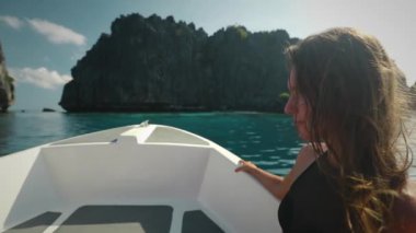 Filipinler 'deki El Nido Adaları' na turistik tekne turunda ağır çekim yapan kadın. Uzun saçlı, beyaz tenli, bikinili kız. Yat okyanusu gezisinin tadını çıkar. Güvertede otur. Yaklaş, yaz tatili seyahatine çık.