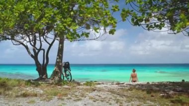 Turist, Fransız Polinezyası 'ndaki Rangiroa Adası' nın nefes kesici güzelliğiyle çevrelenmiş, el değmemiş bir plajda dinleniyor.